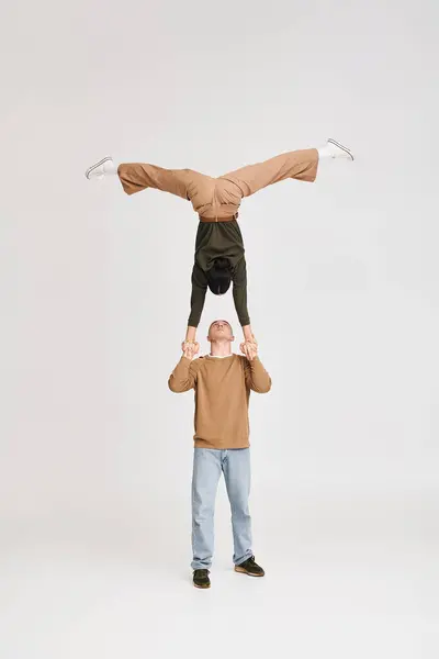 Duo artistico acrobata con donna in testiera sorretta da uomo inginocchiato in studio su sfondo grigio — Foto stock