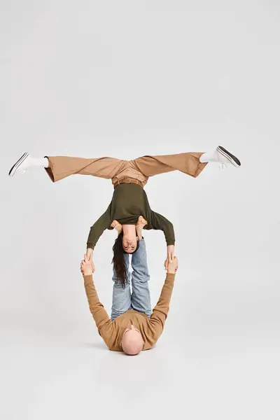 Artistic couple, acrobatic woman holding balancing upside down with support of man in studio — Stock Photo
