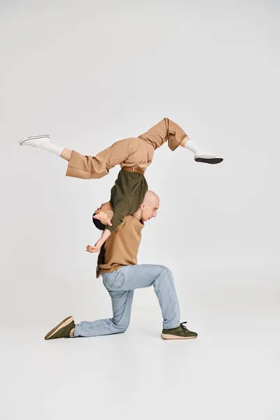 Брюнетка жінка балансує догори ногами з підтримкою чоловіка в повсякденному одязі і репетиції в студії — стокове фото