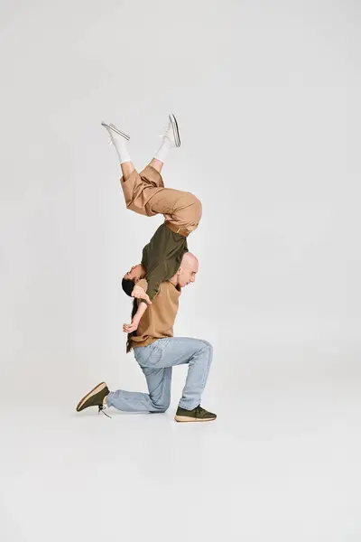 Брюнетка жінка балансує догори ногами з підтримкою чоловіка в повсякденному вбранні під час репетиції в студії — стокове фото