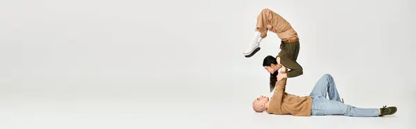 Giovane donna bruna in abbigliamento casual bilanciamento sulle mani di uomo forte, coppia di acrobati banner — Foto stock