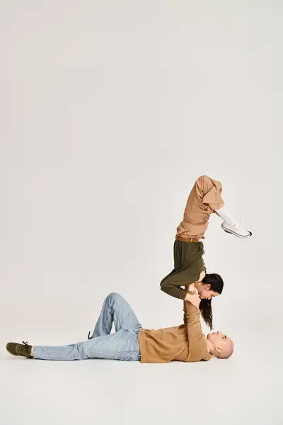 Femme brune en tenue décontractée équilibrant sur les mains d'un homme fort, couple d'acrobates en studio — Photo de stock