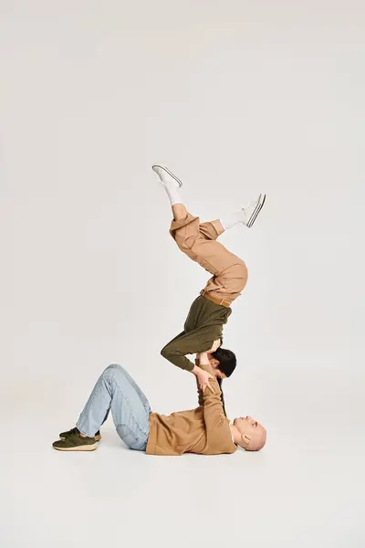 Giovane acrobata femminile in abbigliamento casual bilanciamento sulle mani di uomo forte, coppia che prova in studio — Foto stock