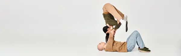 Giovane donna bruna in abbigliamento casual bilanciamento sulle mani dell'uomo, coppia di acrobati banner — Foto stock