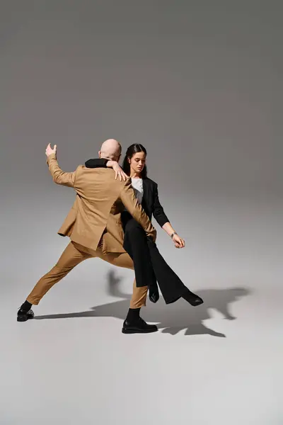 Geschäftsleute in Anzügen führen im Studio vor grauem Hintergrund einen dynamischen Tanzschritt vor, Akrobaten — Stockfoto