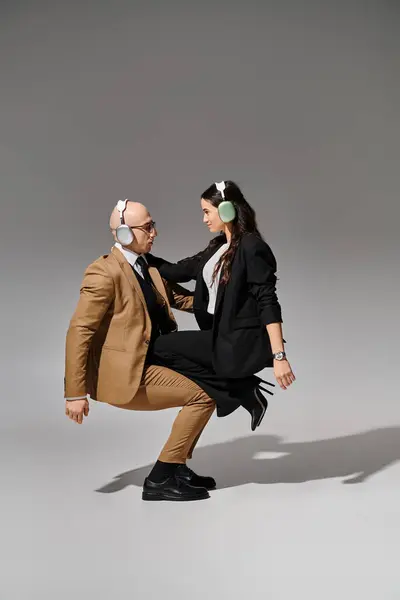 Akrobaten in Anzügen mit drahtlosen Kopfhörern balancieren und tanzen im Büro-Break-Stil, Seitenansicht — Stockfoto