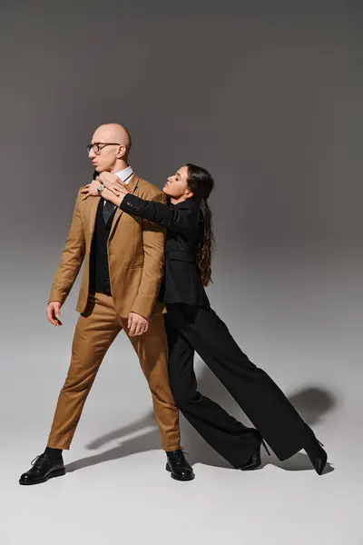 Corporate couple in business attire performing a dance in studio on grey background, support — Stock Photo