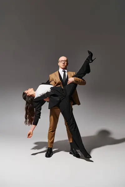 Elegantes Businesspaar in einem dramatischen Tanzlift in neutralem Studio-Ambiente vor grauem Hintergrund — Stockfoto