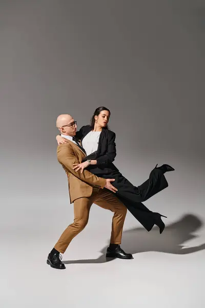 Casal de negócios em ternos elegantes em pose de dança criativa, homem de apoio mulher em estúdio — Fotografia de Stock