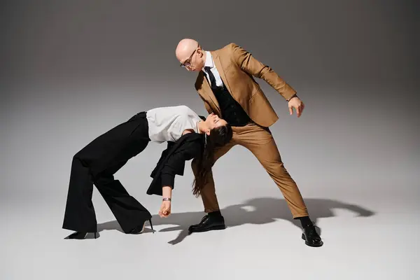 Business partners in a coordinated dance move, suited up together in the studio with grey backdrop — Stock Photo