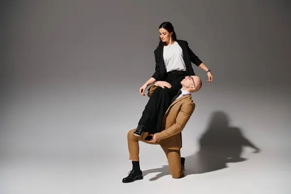 Man in suit and glasses supporting brunette woman during dance performance on grey background — Stock Photo