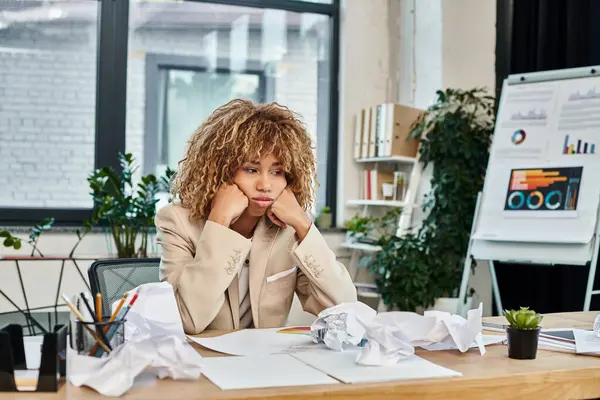 Cansado rizado africano americano mujer de negocios en su escritorio arrugado papeles, estrés en el trabajo concepto - foto de stock