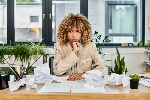 Pensativo encaracolado Africano americano empresária em sua mesa com papéis amassados, estresse no trabalho — Fotografia de Stock