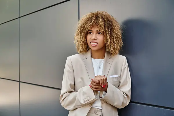 Сподіваюся, афроамериканська бізнес-леді в офісному одязі стоїть біля будівлі офісу, посміхається — стокове фото