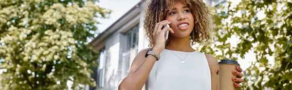 Feliz mulher de negócios afro-americana em aparelho fazendo telefonema e segurando café para ir, banner — Fotografia de Stock