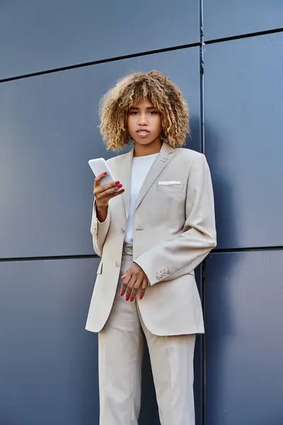 Young and pierced african american businesswoman with curly hair holding her smartphone outdoors — Stock Photo
