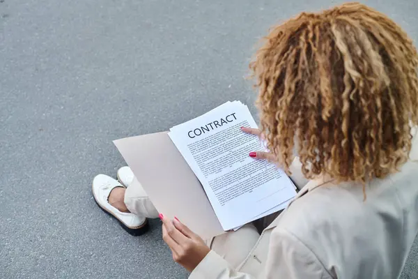 Overhead view of african american curly businesswoman reviewing contract on the go outdoors — Stock Photo