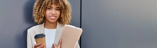 Professional headshot banner, happy african american woman with coffee and folder standing by wall — Stock Photo