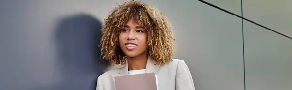 Cheerful young african american businesswoman in formal wear holding folder by office wall, banner — Stock Photo