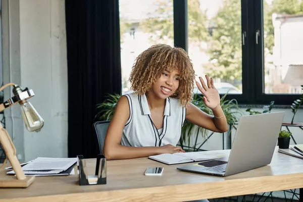 Heureuse femme d'affaires afro-américaine avec un sourire amical agitant la main lors d'un appel vidéo sur ordinateur portable — Photo de stock