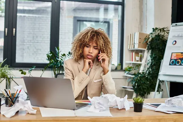 Dépassé femme d'affaires afro-américaine multitâche près ordinateur portable et le chaos de la paperasserie — Photo de stock