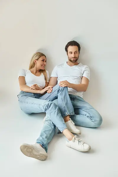 Um casal romântico, o homem e a mulher, sentam-se juntos no chão, compartilhando um momento íntimo de conexão e amor. — Fotografia de Stock