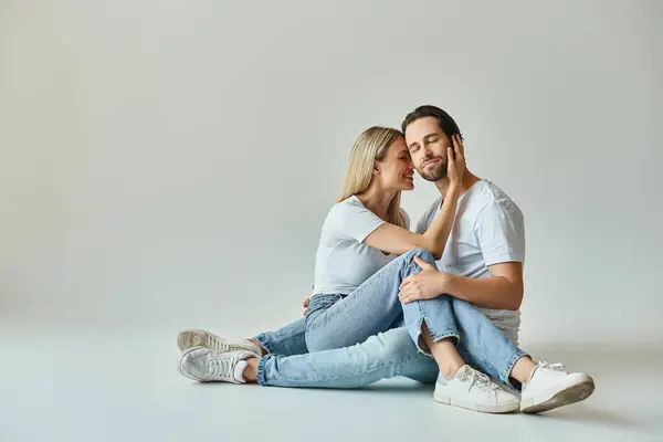 Una coppia, che incarna romanticismo, seduta a terra in un caldo abbraccio circondata da un'atmosfera tranquilla. — Foto stock