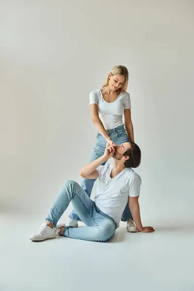 A man in casual attire sits peacefully on the ground next to a woman, sharing a moment of quiet togetherness. — Stock Photo