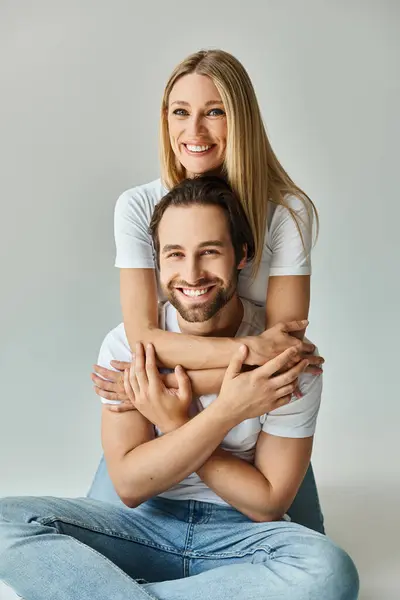 A man, seated on the ground, carries a woman on his back in a romantic and intimate gesture of togetherness and connection. — Stock Photo
