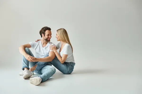 Happy couple, wrapped in an intimate embrace, sitting close on the ground in a romantic moment. — Stock Photo