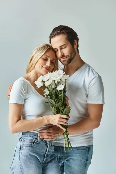 Um momento romântico capturado como uma mulher ternamente mantém um buquê de flores ao lado de um homem, exalando amor e conexão. — Fotografia de Stock
