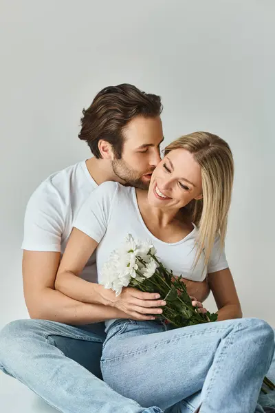 Un couple passionné, symbolisant la romance, assis parmi des fleurs vibrantes, partageant des moments intimes ensemble — Photo de stock