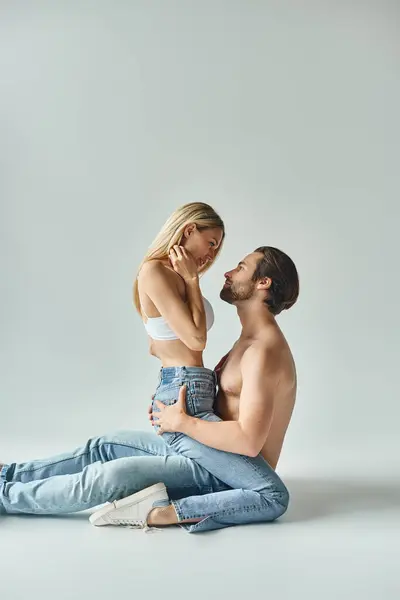 Un uomo e una donna, trasudando un fascino magnetico, condividono un momento intimo seduti a terra. — Stock Photo