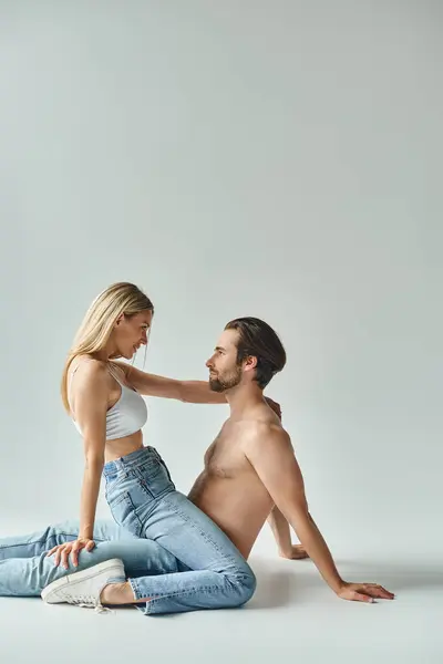 Un homme s'agenouille tendrement à côté d'une femme sur le sol, incarnant un moment d'intimité partagée et de connexion entre un couple sexy. — Photo de stock