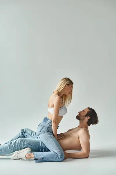 A man and a woman, exuding magnetic energy, sit closely together on the ground in a tender moment of intimacy and connection. — Stock Photo
