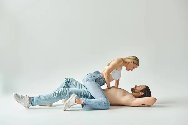 Un hombre y una mujer, encarnando el romance, tendidos uno al lado del otro en el suelo, sus cuerpos entrelazados en un apasionado abrazo. - foto de stock