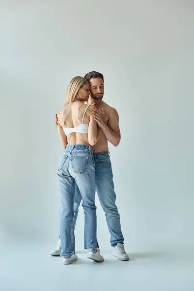 Un uomo e una donna che indossano jeans si abbracciano in un momento romantico e intimo. — Foto stock