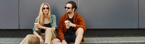 Un couple, exsudant sexiness et romance, s'assoit étroitement ensemble sur un trottoir dans un cadre urbain. — Photo de stock
