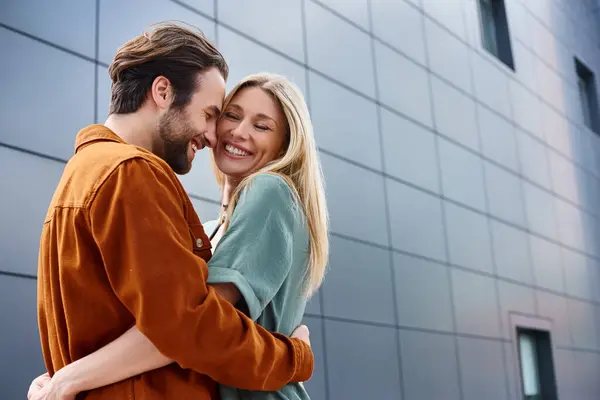 A sensual moment between a man and woman, wrapped in each others arms in front of a striking building. — Stock Photo