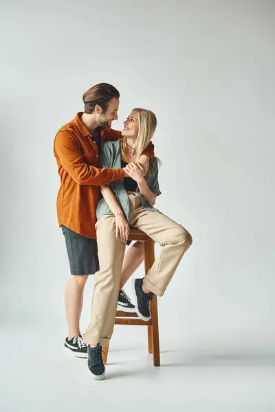Чоловік і жінка, виключаючи романтику, сидять тісно разом на стільці. — стокове фото