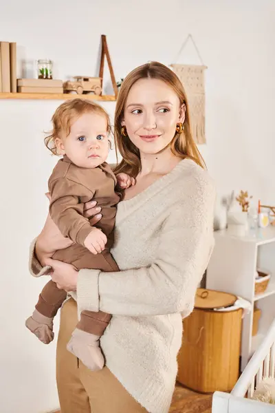 Joyeux attrayant femme avec mignon petit fils dans les mains debout dans la chambre d'enfant, maternité moderne — Photo de stock