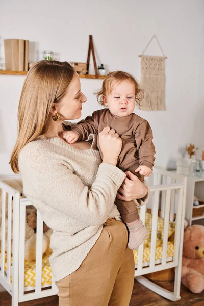 Young attractive woman holding adorable little son in cozy nursery room, blissful motherhood — Stock Photo