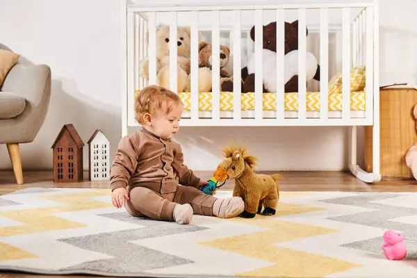 Adorável criança menino sentado no chão e brincando com brinquedo cavalo perto berço em quarto de crianças — Fotografia de Stock