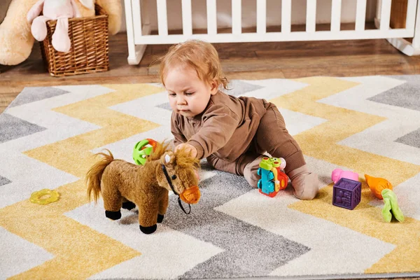 Criança adorável e sentado no chão e brincando com brinquedos no quarto de berçário acolhedor, infância feliz — Fotografia de Stock