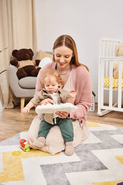 Mulher alegre brincando com o bebezinho perto do berço no chão no quarto do berçário, maternidade feliz — Fotografia de Stock