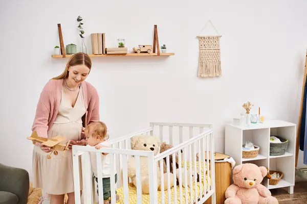 Sonriente mujer embarazada jugando con juguete avión y niño pequeño en habitación de la guardería en casa, maternidad - foto de stock