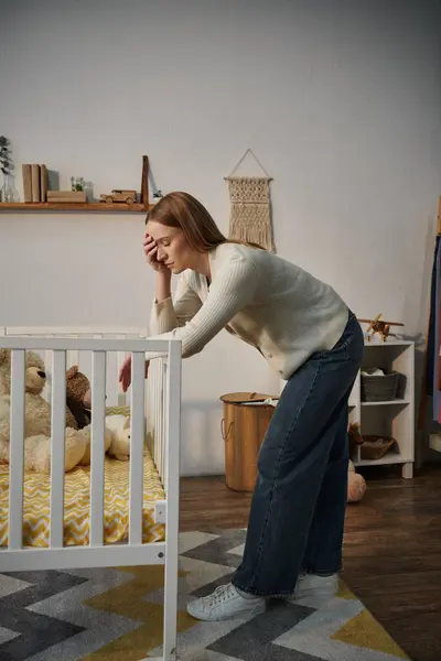 Frustrierte Frau steht neben Krippe mit Plüschtieren in trostlosem Kinderzimmer zu Hause, unglücklich — Stockfoto