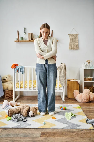 Виснажена і безнадійна жінка з м'якою іграшкою, що стоїть в дитячій кімнаті вдома, безсердечний момент — стокове фото