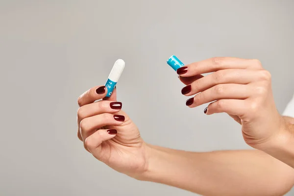 Tampon hygiénique dans les mains d'une jeune femme inconnue avec vernis à ongles sur fond gris, photo de l'objet — Photo de stock