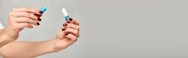 Tampon hygiénique dans les mains d'un jeune modèle féminin inconnu sur fond gris, photo d'objet, bannière — Photo de stock